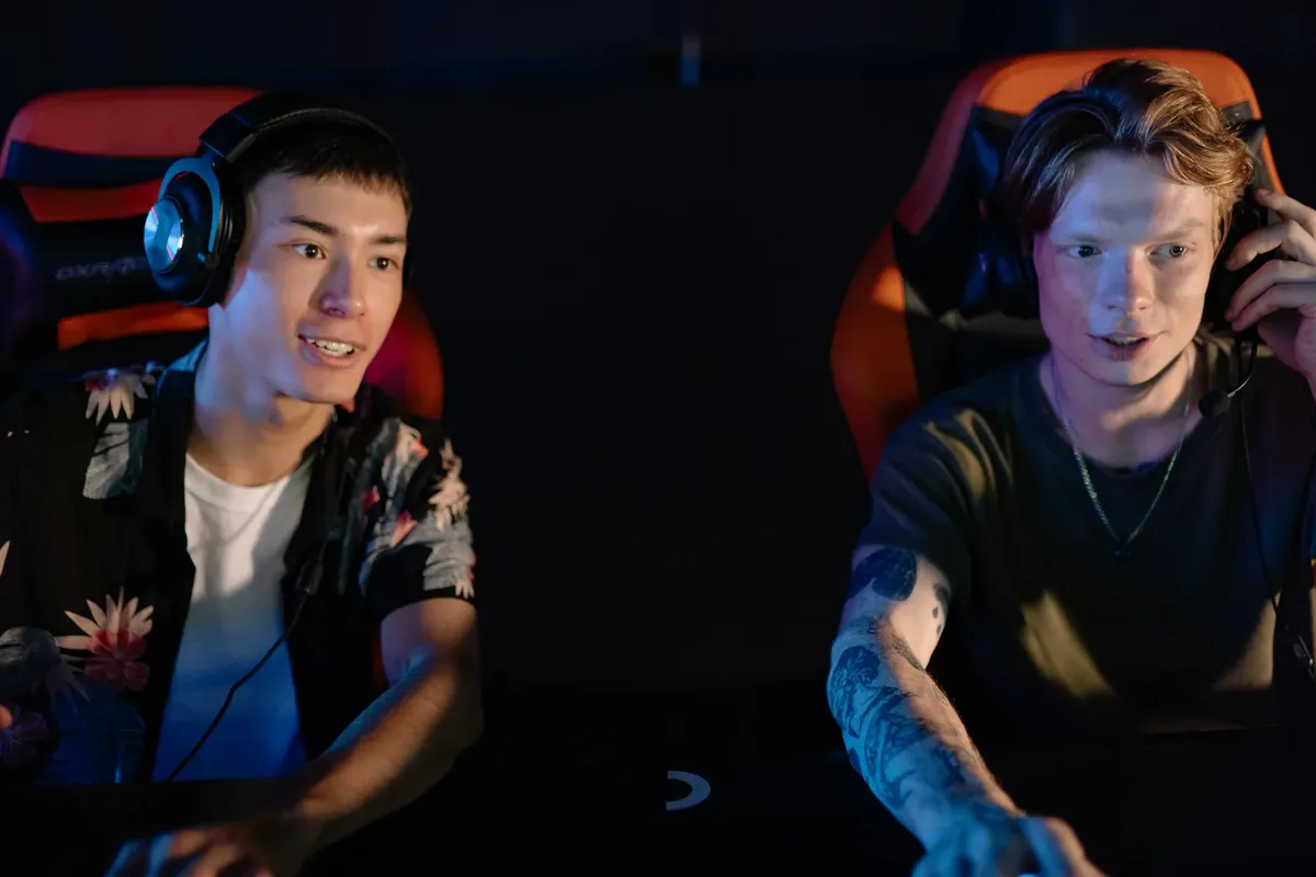 Two young men focused on an intense gaming session in a dark room, participating in a team esports tournament.