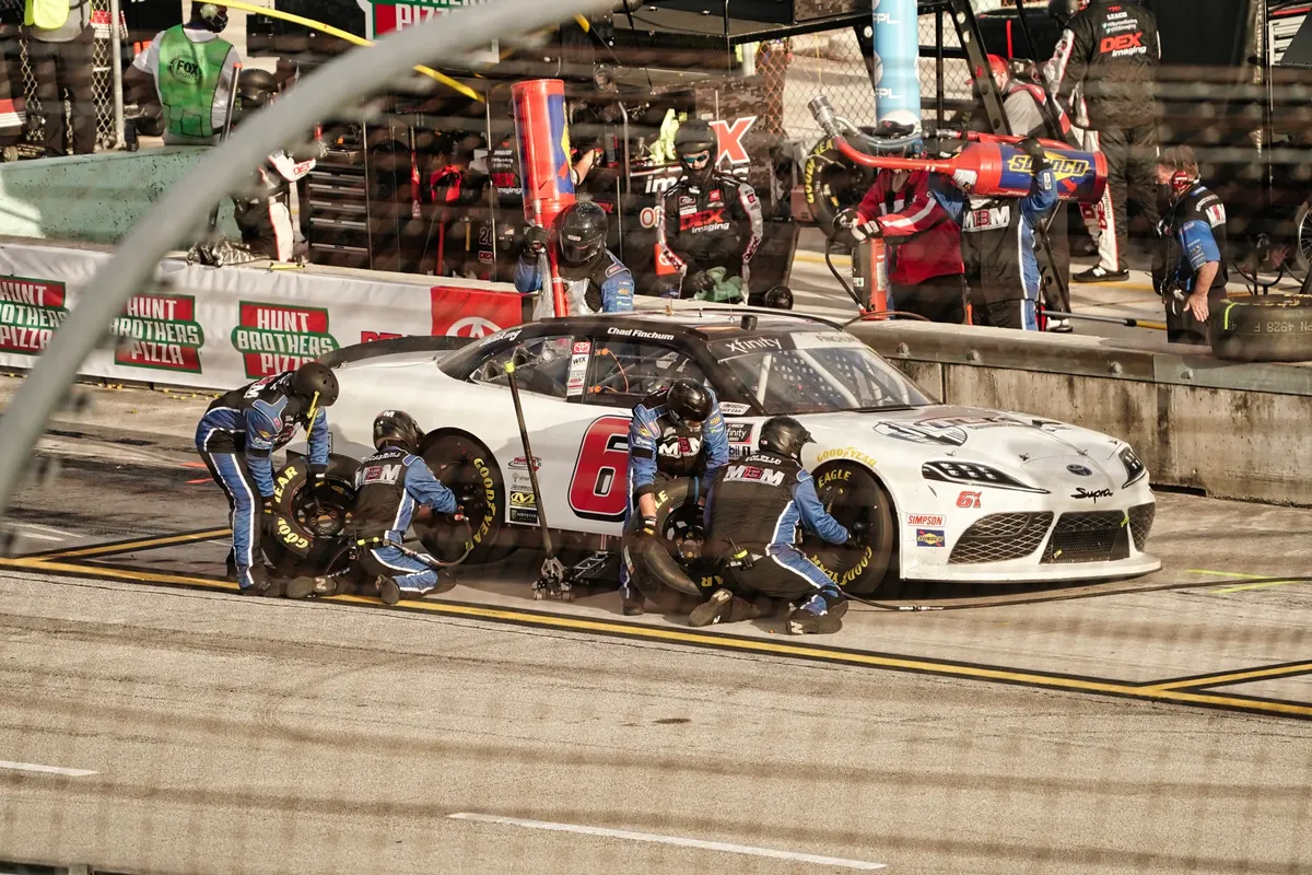 Intense pit stop during a car race in Miami, featuring teamwork and precision.