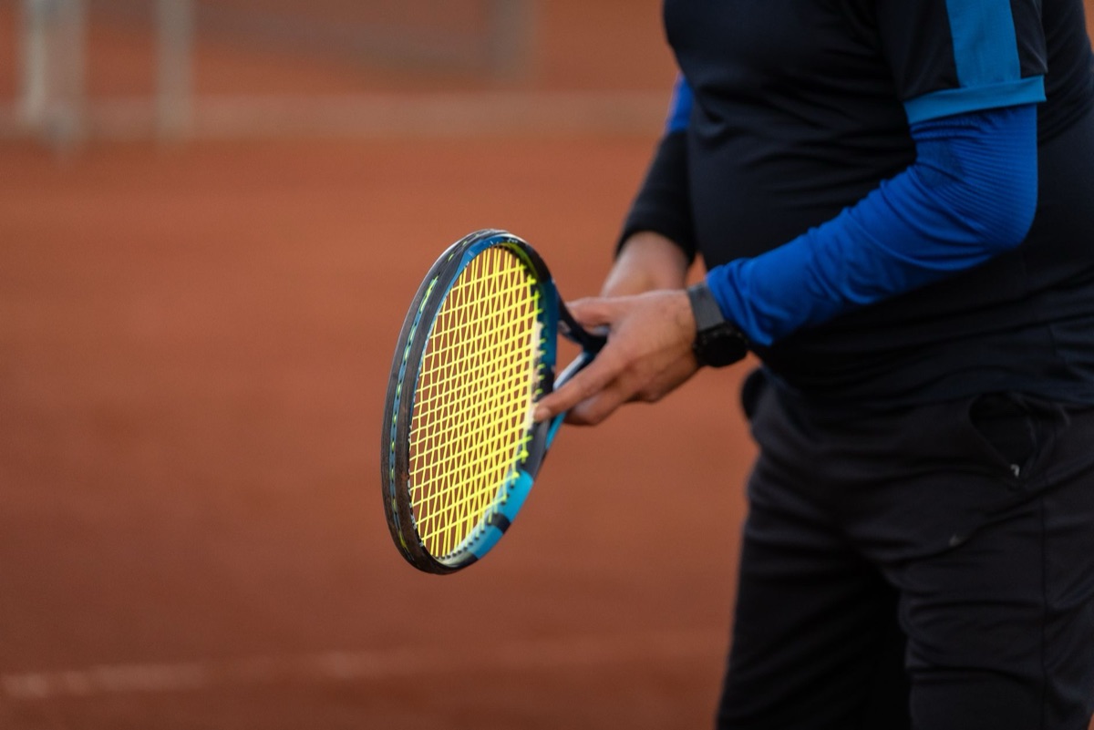 A close-up shot of a person holding a tennis racket with a western grip.