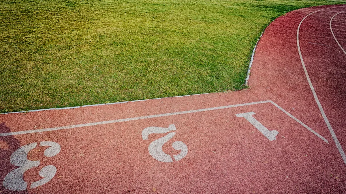 A bird's-eye view of a vibrant outdoor running track and lush green sports field.
