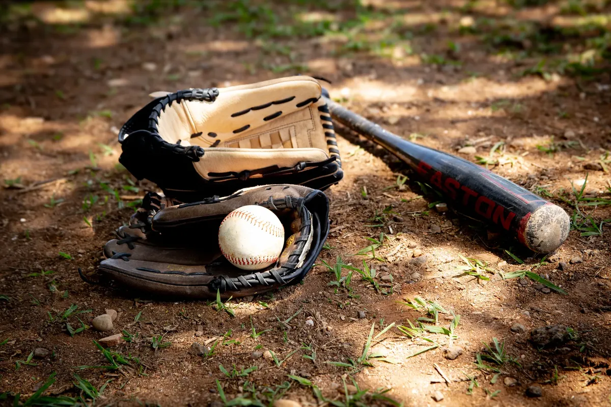 農村の泥道に baseball の装备、ボール、バット、グローブが撮影されたクローズアップ。