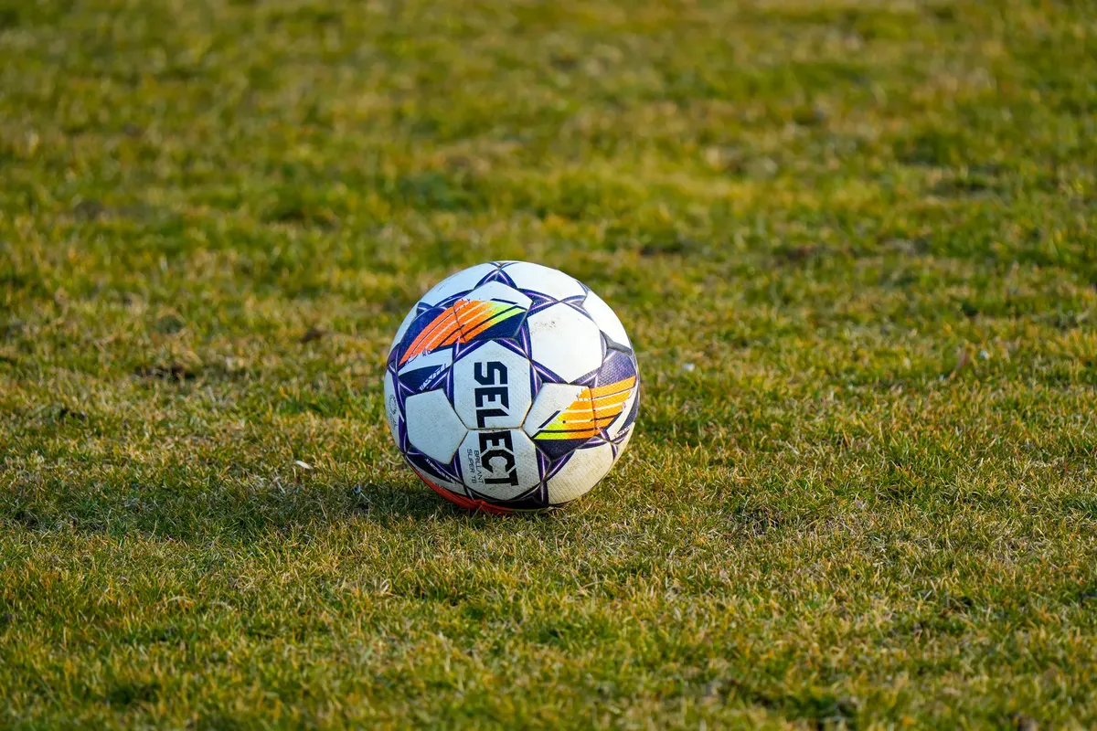 草の場に日光の中、サッカーのボールが写っているクローズアップ。完璧なスポーツ施設のシーン。