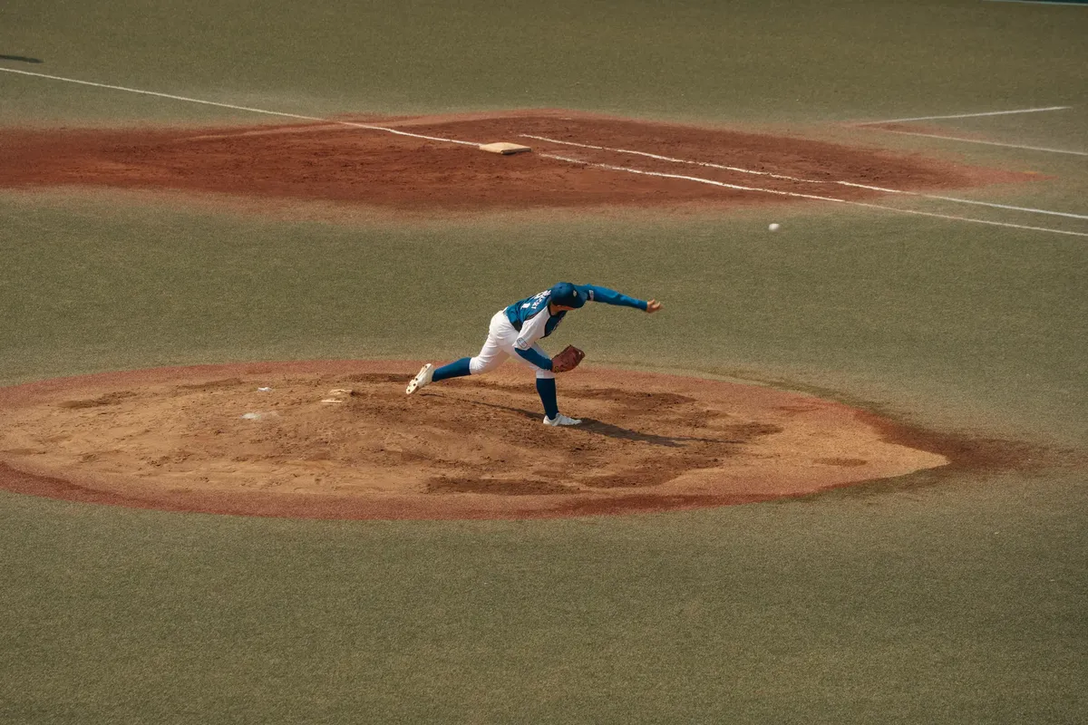A skilled baseball pitcher delivers a pitch on a sunlit field in Tokyo, Japan. Captured in dynamic motion.