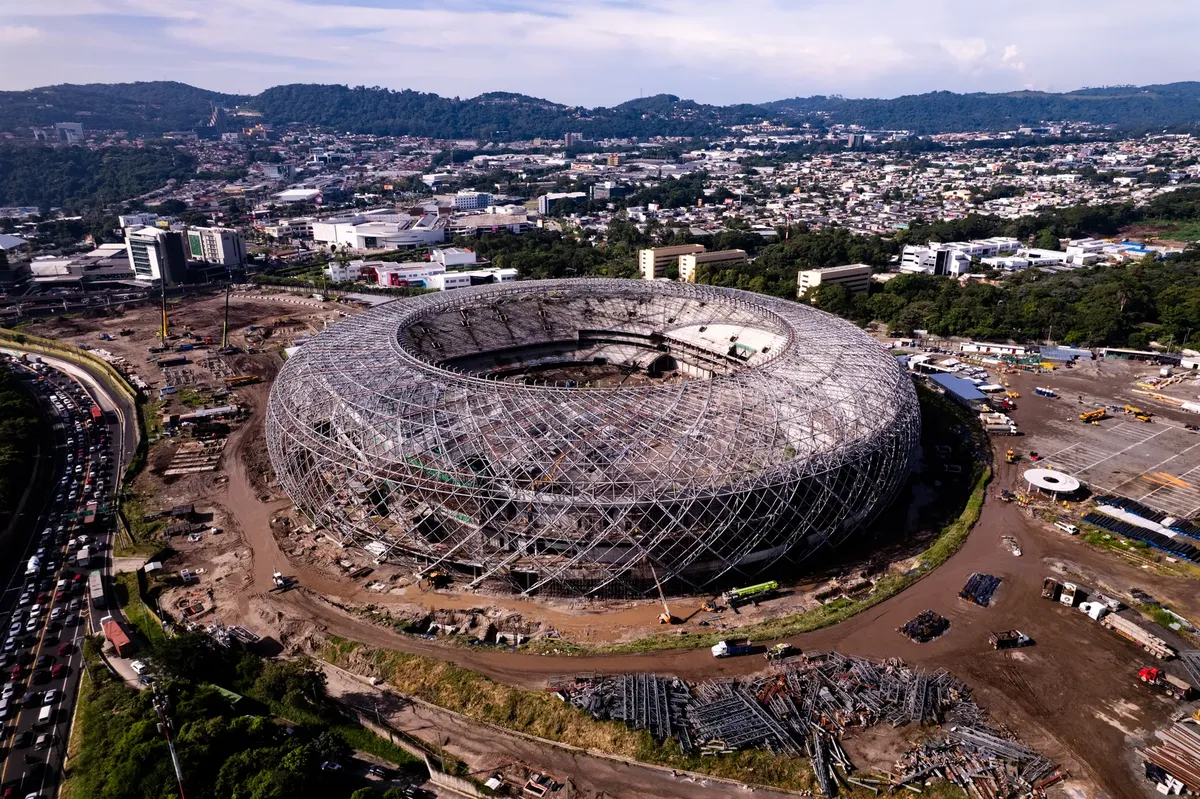 Aerial shot of a stadium under construction in San Salvador, El Salvador with cityscape in the background.
